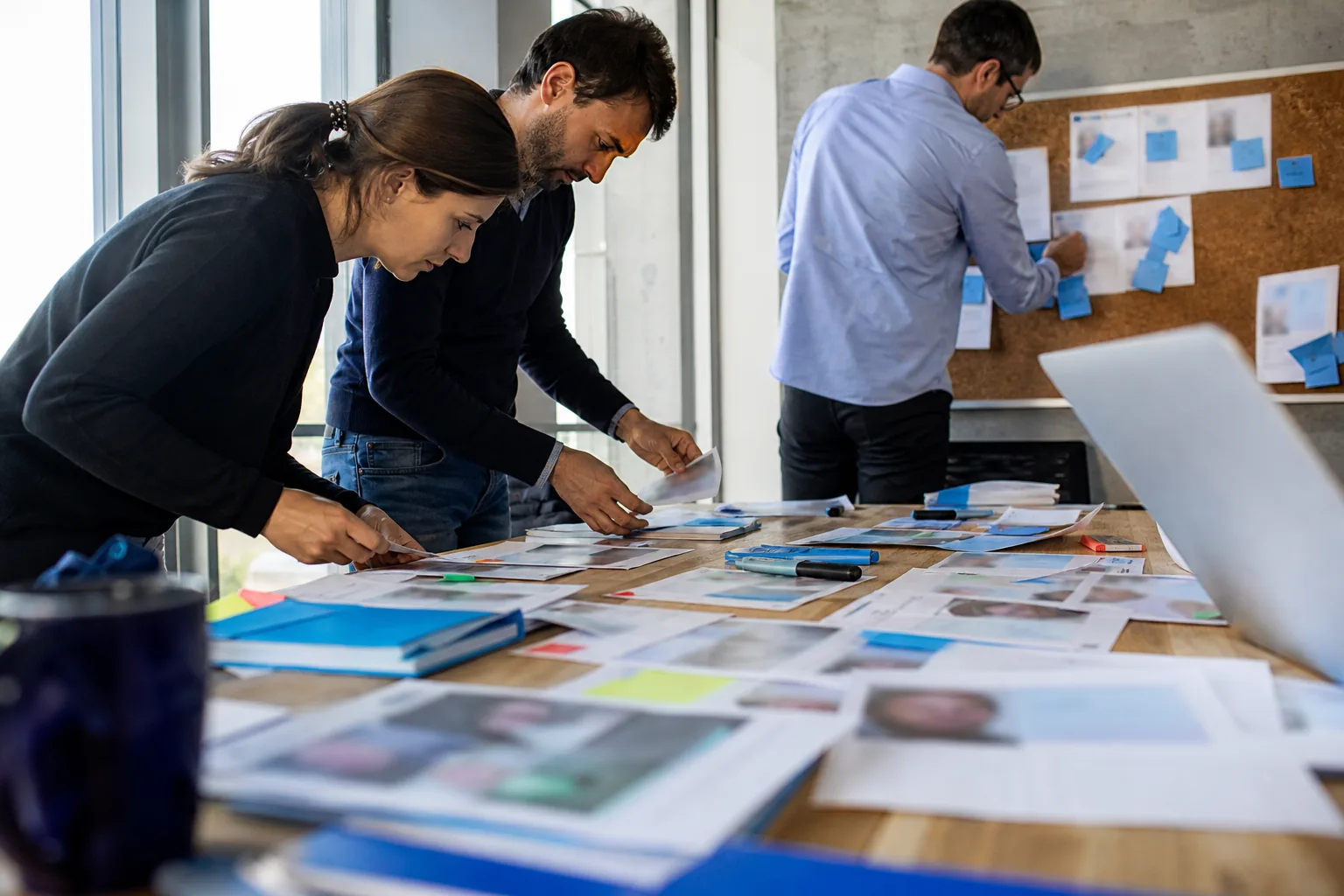 Strategy team sorting printed competitor profiles into segments on a meeting table